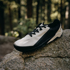 Black and white sneaker on a rock with a forest background
