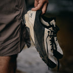 Person holding a worn hiking shoe with visible brand logo.